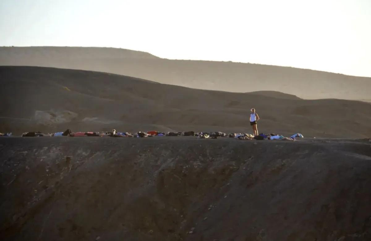 A tiny figure doing a headstand on a volcanic ridge