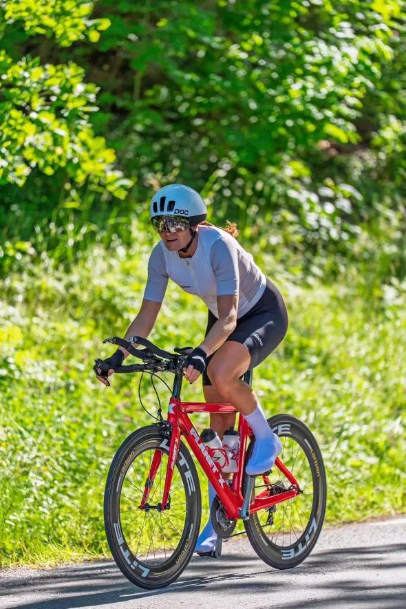 Emma on her red time-trial bike on a sunny country road